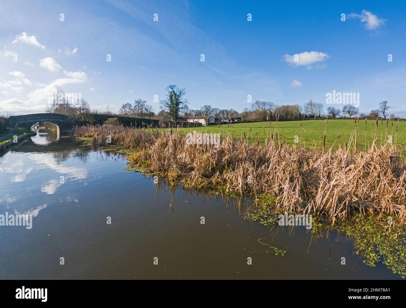 Vista di un paesaggio rurale inglese campagna sul canale britannico della via d'acqua con vecchio ponte stradale in pietra Foto Stock
