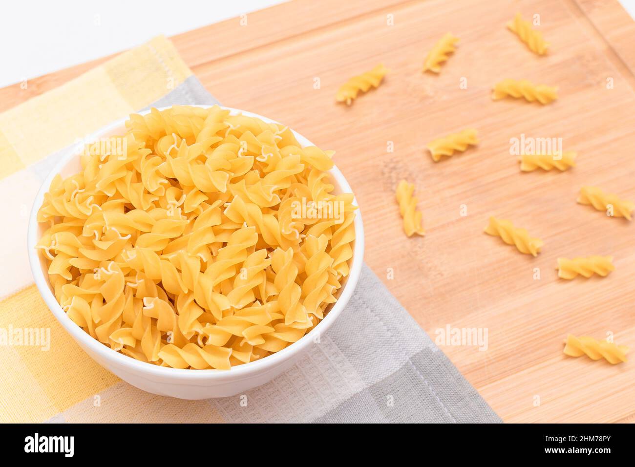 Pasta di Fusilli non cotta in ciotola bianca su tavola di legno. Macaroni crudi e secchi. Cibo malsano e grasso. Cultura Italiana Foto Stock