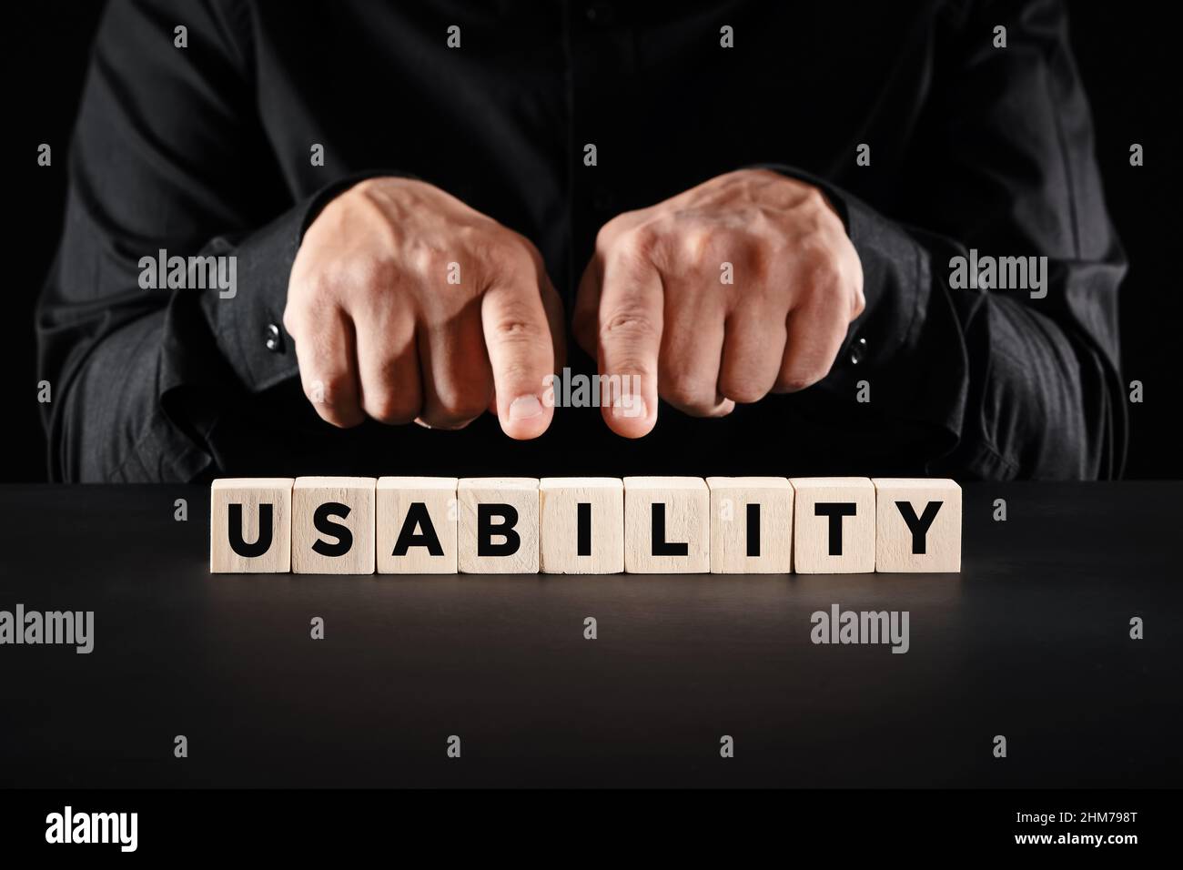 Mani maschili che puntano alla parola usabilità su blocchi di legno. Concetto di qualità o soddisfazione dell'esperienza utente. Foto Stock