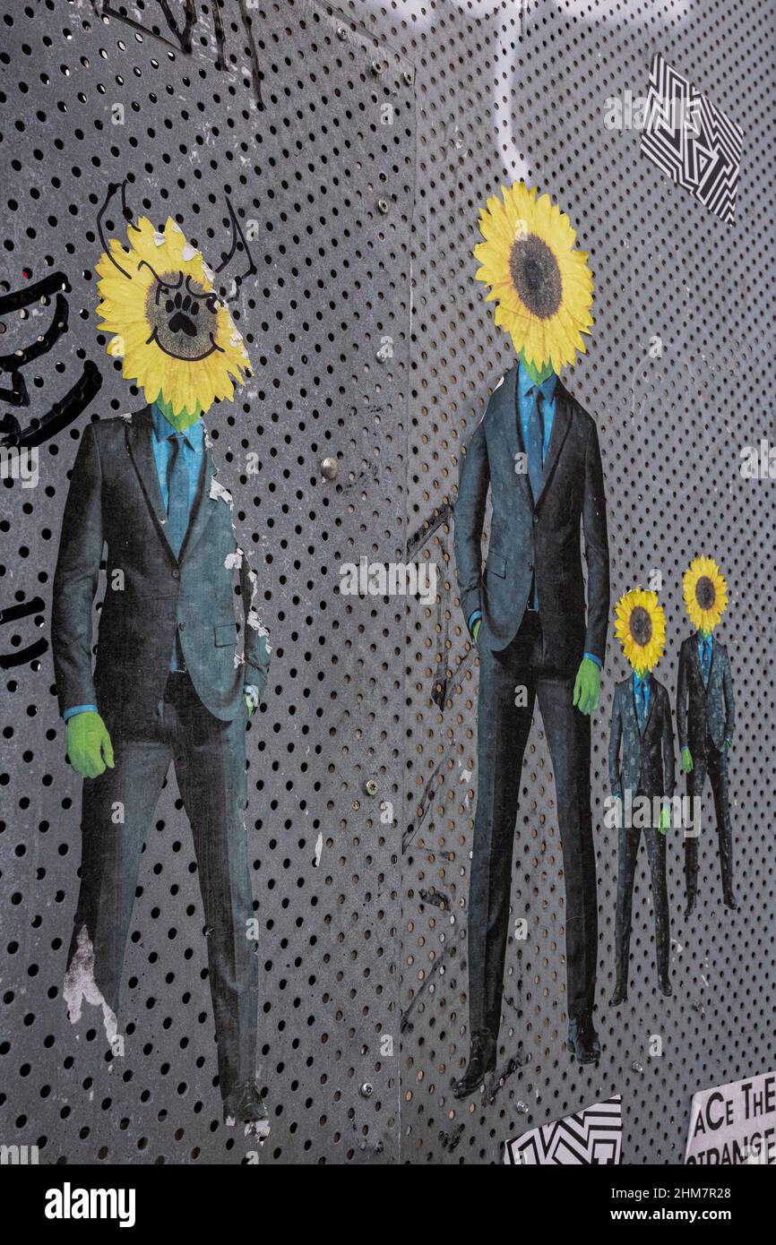 Surrealismo e affari , testa di girasole invece di un uomo in abito nero a parete . Foto Stock