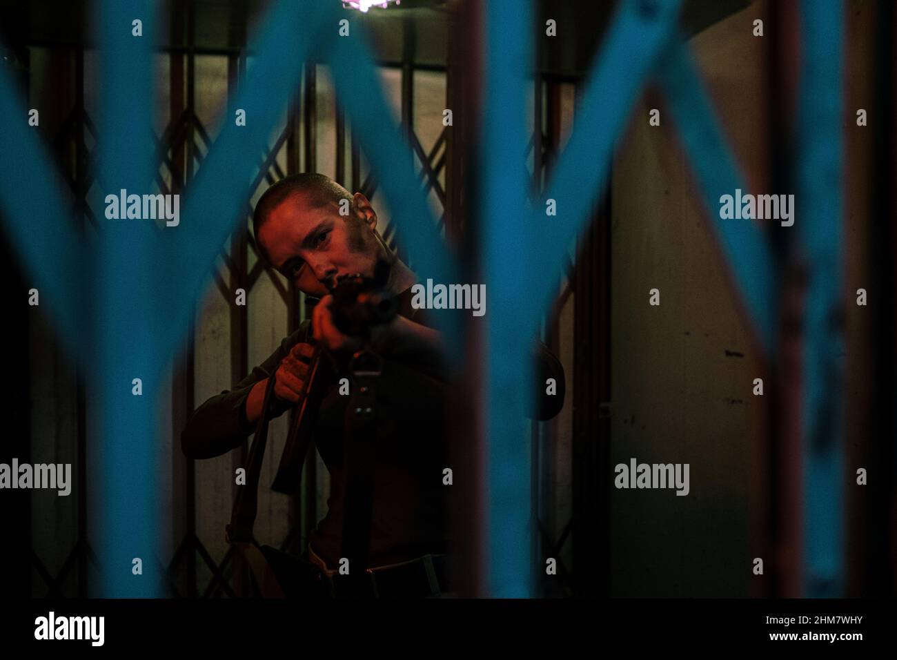 Ritratto in vita di donna dura con pistola a punta buzz taglio alla fotocamera mentre si trova in una stanza buia pronta a combattere, spazio copia Foto Stock
