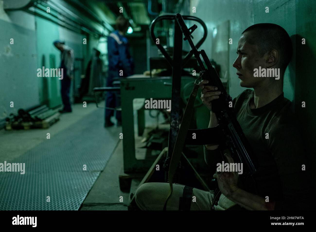 Ritratto della vista laterale della donna soldato che tiene la pistola mentre aspetta nel nascondiglio per gruppo di zombie nel corridoio, spazio copia Foto Stock