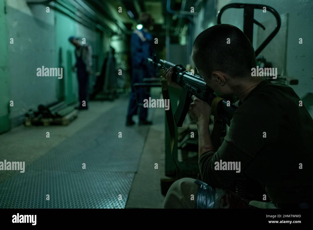 Vista posteriore di una soldato femminile che spara zombie in un corridoio scuro, spazio copia Foto Stock