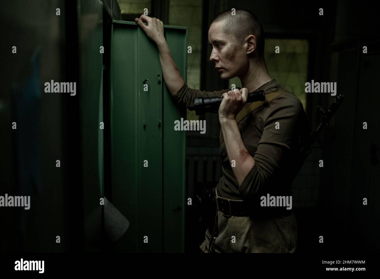 Vista laterale ritratto di giovane donna dura cerca armadietti con torcia in camera industriale scuro, spazio copia Foto Stock