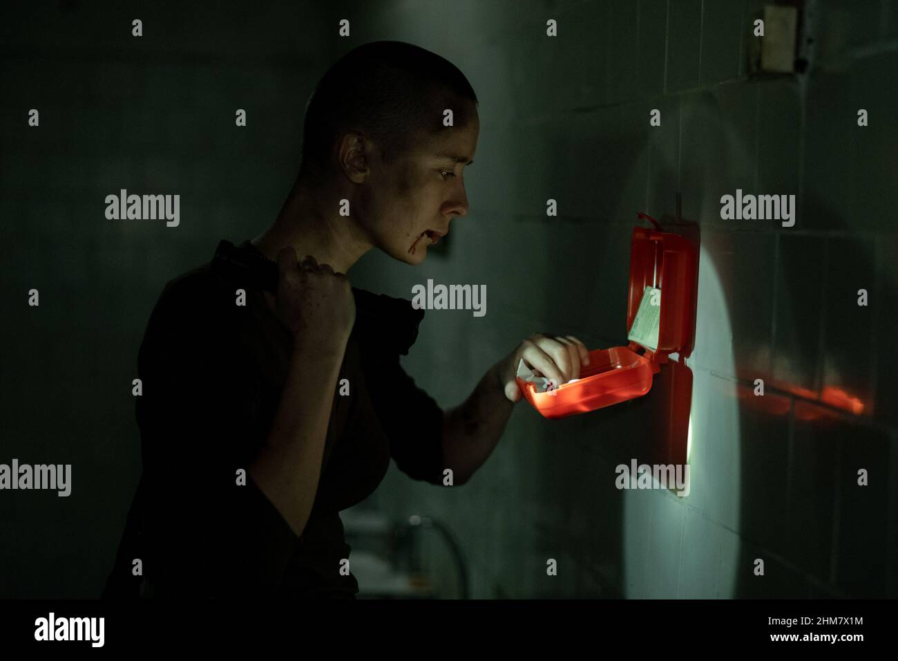 Vista laterale ritratto di giovane donna dura controllare kit di pronto soccorso e tenere la torcia in scuro sopravvivenza impostazione, copia spazio Foto Stock