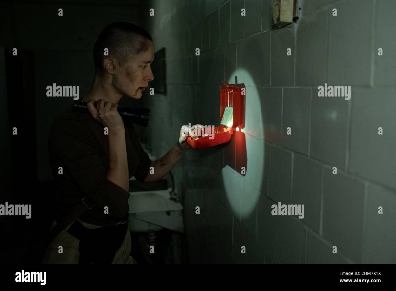Vista laterale ritratto di donna dura controllo kit di pronto soccorso con torcia in scuro sopravvivenza impostazione, spazio copia Foto Stock