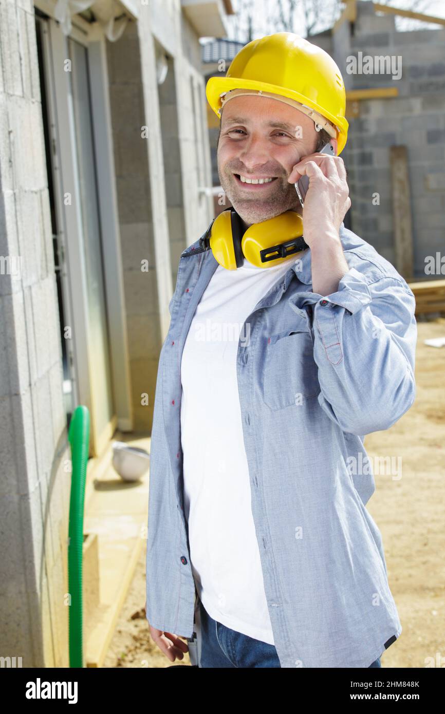 uomo di lavoro che utilizza uno smartphone al di fuori di una proprietà Foto Stock