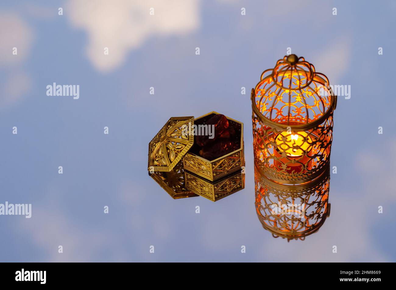Lanterna dorata con datteri frutto riflessione da sfondo specchio per la festa musulmana del mese santo di Ramadan Kareem. Foto Stock