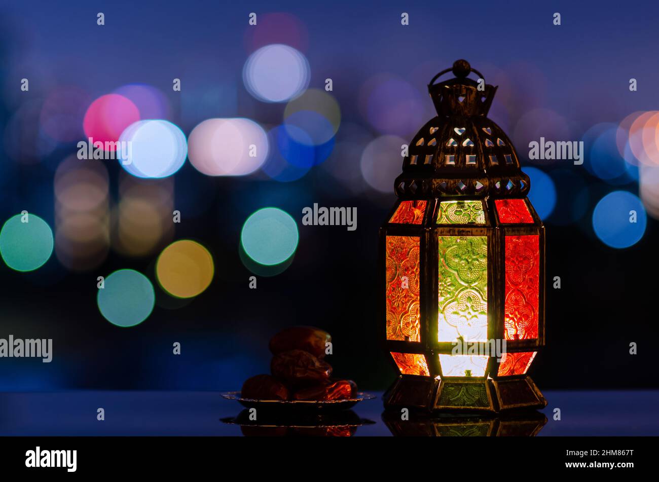 Lanterna e piccolo piatto di datteri frutta con cielo notturno e città bokeh sfondo chiaro per la festa musulmana del mese santo di Ramadan Kareem. Foto Stock