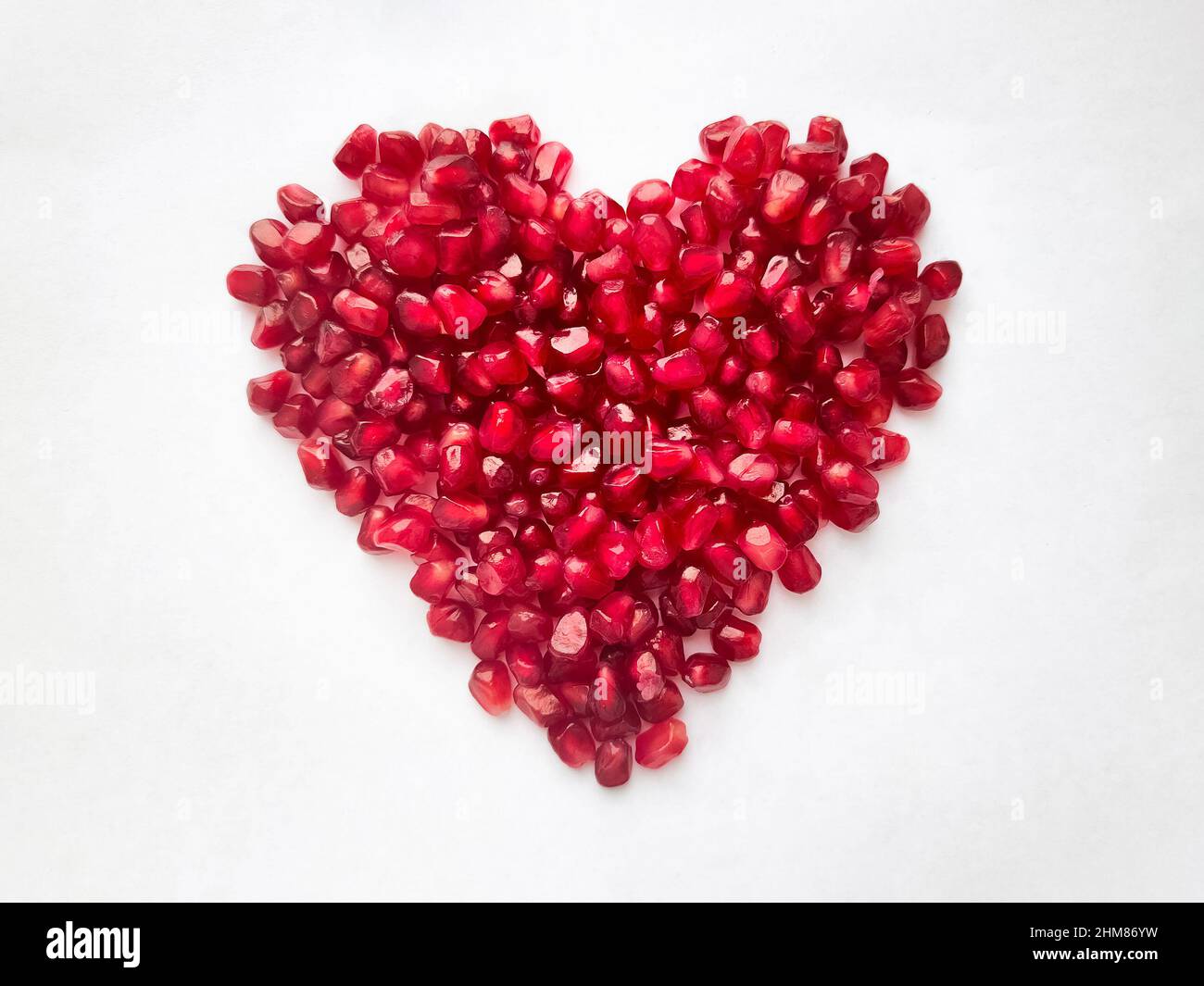 Cuore da semi di melograno isolato su sfondo bianco. Forma del cuore. Foto di alta qualità Foto Stock