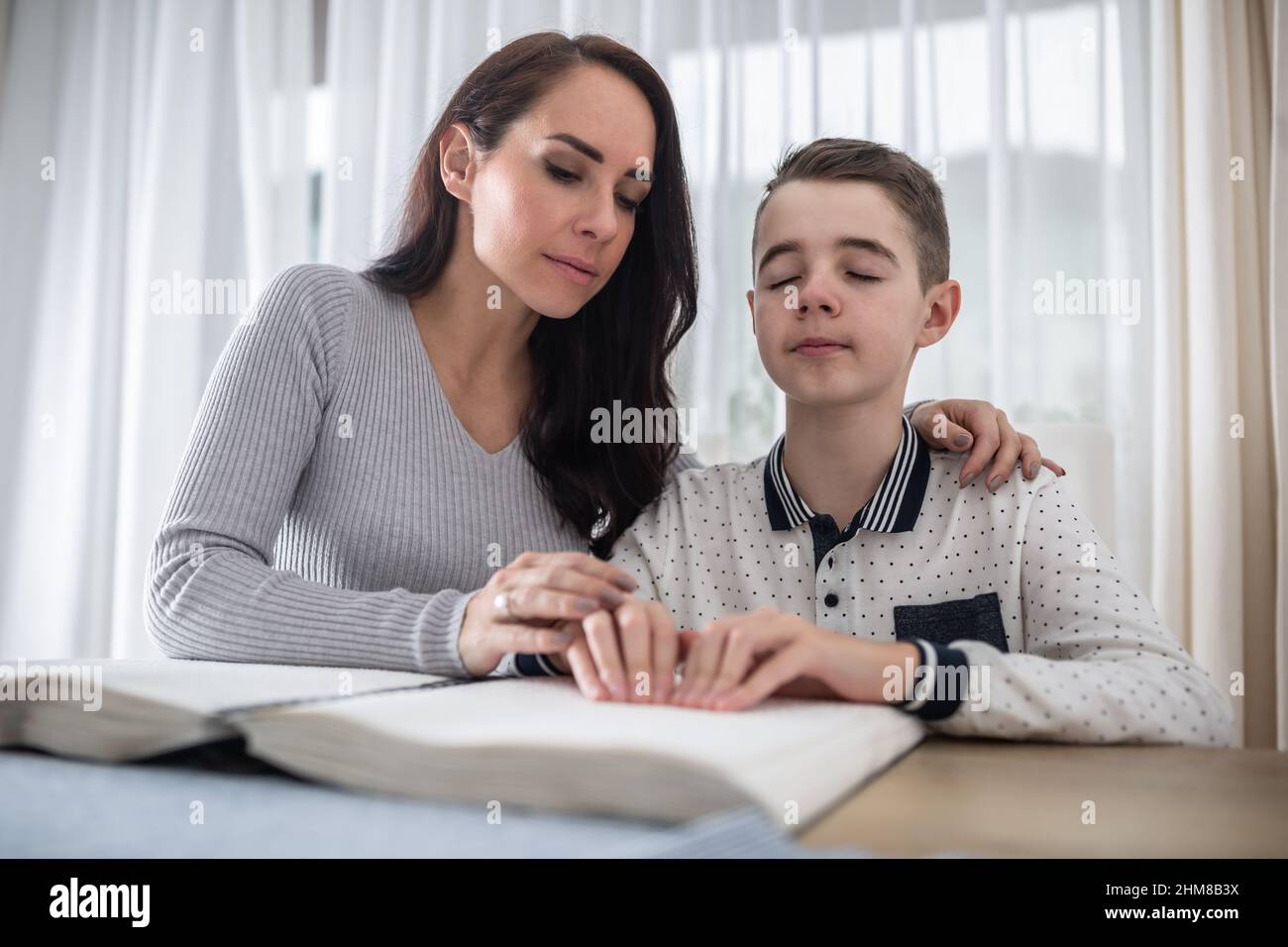 Donna aiuta il ragazzo cieco a leggere un libro in braille. Foto Stock