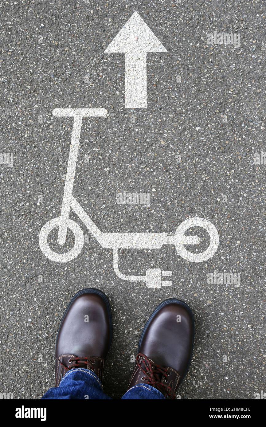 Uomo persone scooter elettrico e-scooter strada cartello freccia eco friendly mobilità ritratto formato trasporto città trasporto Foto Stock