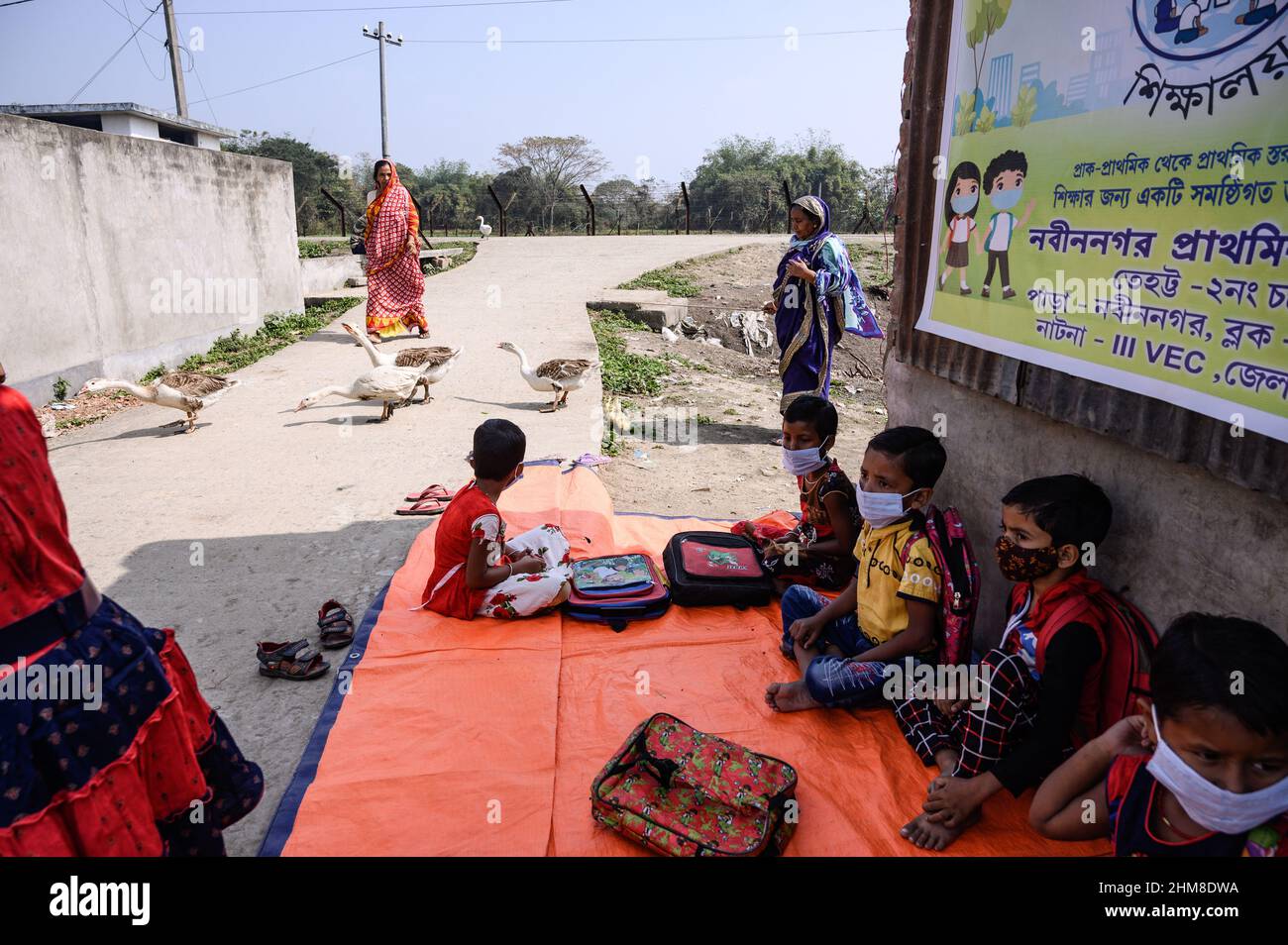 Nabin Nagar, Bengala Occidentale, India. 7th Feb 2022. Il governo dello Stato del Bengala occidentale ha lanciato "'˜Paray Shikshalaya' a decorrere dal 7th febbraio, Uno sforzo di scolarizzazione basato sulla comunità nei quartieri che mira gli studenti primari a mirare al programma è quello di svezzare una grande sezione di studenti che ha abbandonato il sistema di istruzione formale negli ultimi due anni a causa della chiusura delle scuole, a causa di Covid-19. Una classe preprimaria della scuola elementare di confine India-Bangladesh è stata portata su una strada vuota accanto alla recinzione a Nabin Nagar, ci sono occasionalmente animali domestici che entrano. (Credito Foto Stock