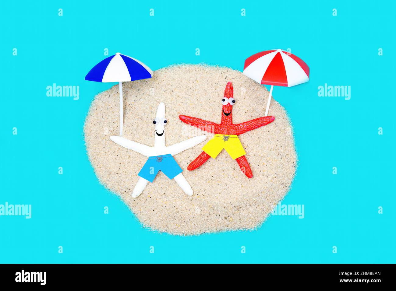 Due simpatici personaggi di stelle marine con occhi googly che si godono il sole su una vacanza in spiaggia di sabbia. Foto Stock