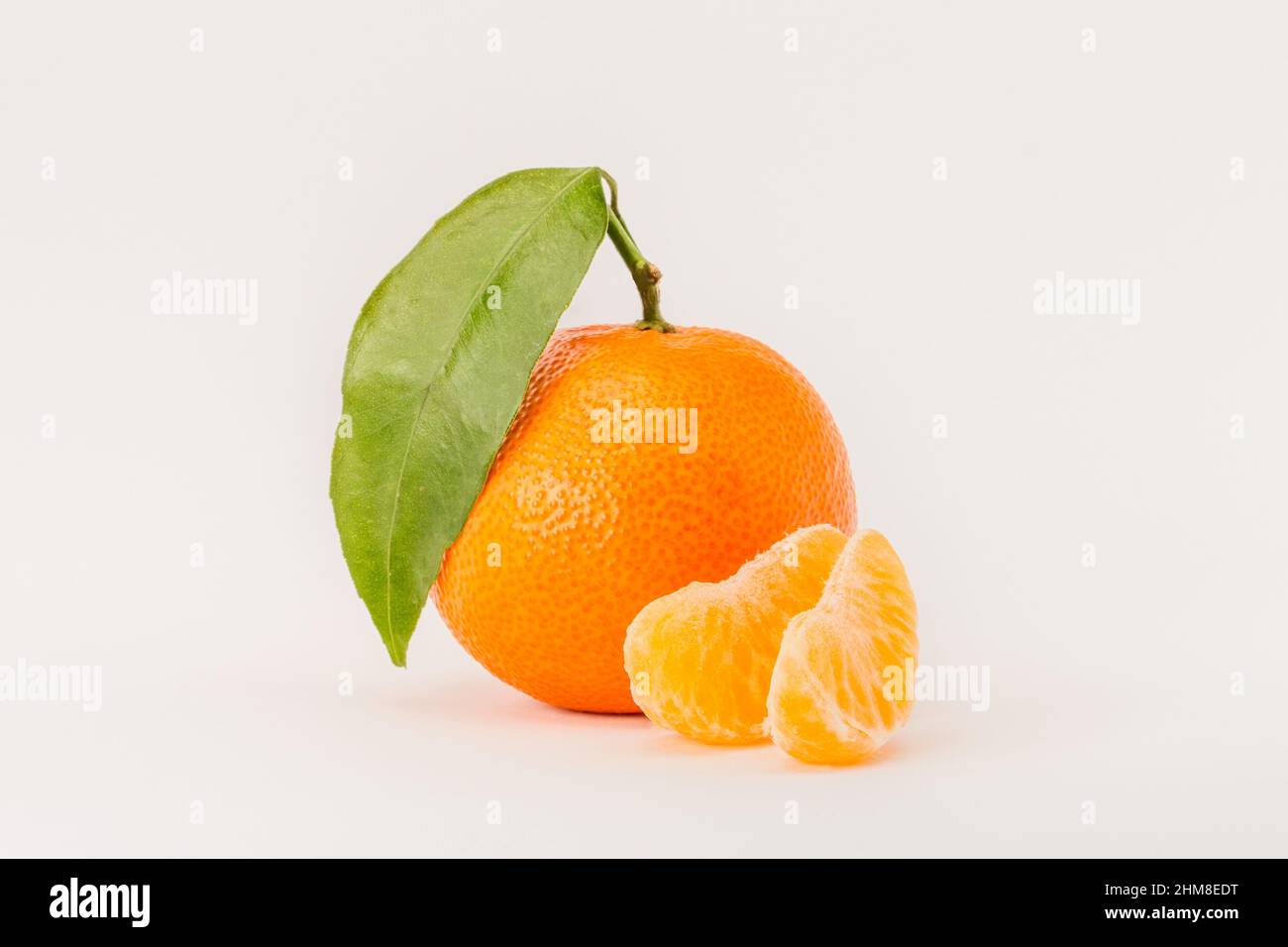 Agrumi di mandarino maturo con foglia verde e fettine di mandarino isolate e su sfondo bianco Foto Stock