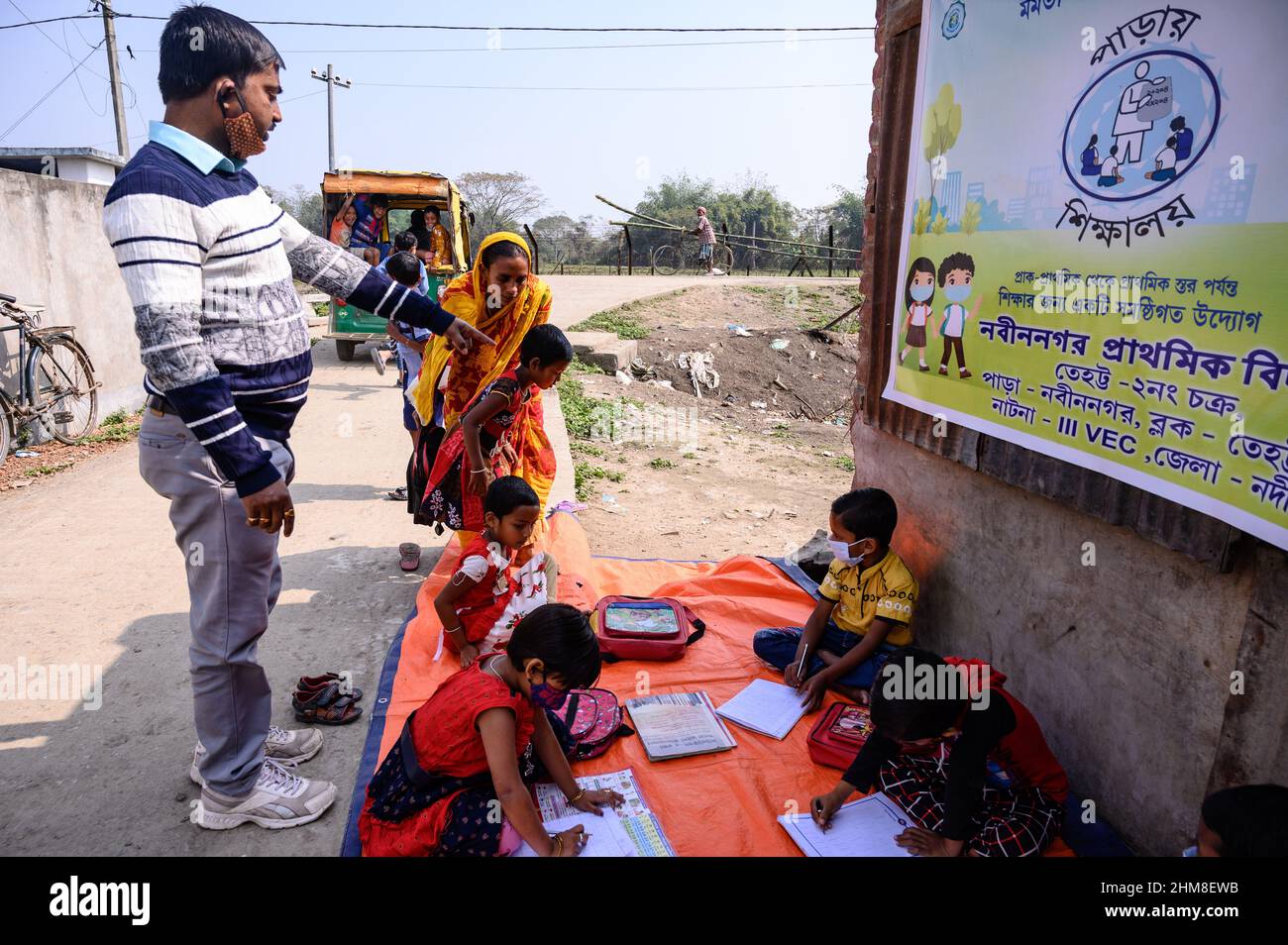 Nabin Nagar, Bengala Occidentale, India. 7th Feb 2022. Il governo dello Stato del Bengala occidentale ha lanciato "'˜Paray Shikshalaya' a decorrere dal 7th febbraio, Uno sforzo di scolarizzazione basato sulla comunità nei quartieri che mira gli studenti primari a mirare al programma è quello di svezzare una grande sezione di studenti che ha abbandonato il sistema di istruzione formale negli ultimi due anni a causa della chiusura delle scuole, a causa di Covid-19. Una classe preprimaria della scuola elementare di confine India-Bangladesh è stata portata su una strada vuota accanto alla recinzione a Nabin Nagar, ci sono occasionalmente animali domestici che entrano. (Credito Foto Stock