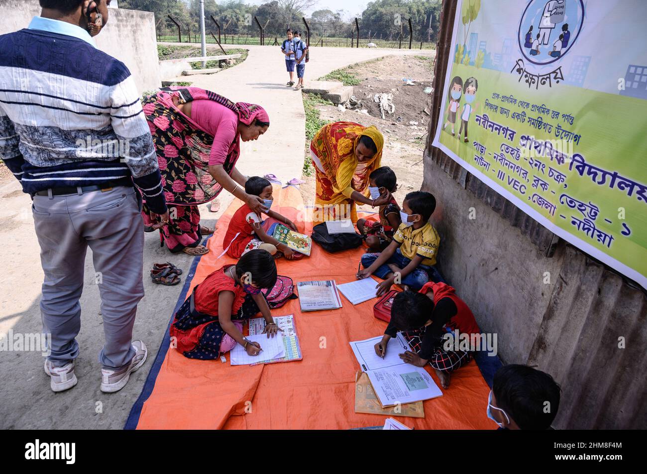 Nabin Nagar, Bengala Occidentale, India. 7th Feb 2022. Il governo dello Stato del Bengala occidentale ha lanciato "'˜Paray Shikshalaya' a decorrere dal 7th febbraio, Uno sforzo di scolarizzazione basato sulla comunità nei quartieri che mira gli studenti primari a mirare al programma è quello di svezzare una grande sezione di studenti che ha abbandonato il sistema di istruzione formale negli ultimi due anni a causa della chiusura delle scuole, a causa di Covid-19. Una classe preprimaria della scuola elementare di confine India-Bangladesh è stata portata su una strada vuota accanto alla recinzione a Nabin Nagar, ci sono occasionalmente animali domestici che entrano. (Credito Foto Stock