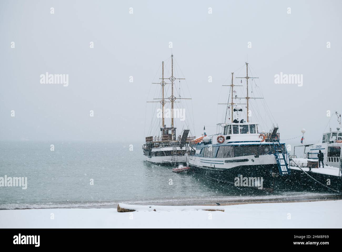 Gelendzhik, Russia, 24 gennaio 2022: Barche marine vicino al molo durante una nevicata in inverno. Foto Stock