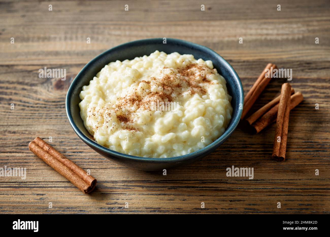ciotola di budino di latte di riso con cannella su tavolo da cucina in legno Foto Stock