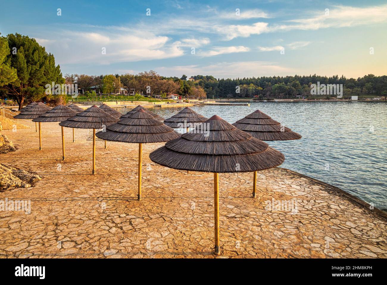 Ombrelloni sulla spiaggia al tramonto. La Laguna Blu di Porec - Istria, Croazia, Europa. Foto Stock