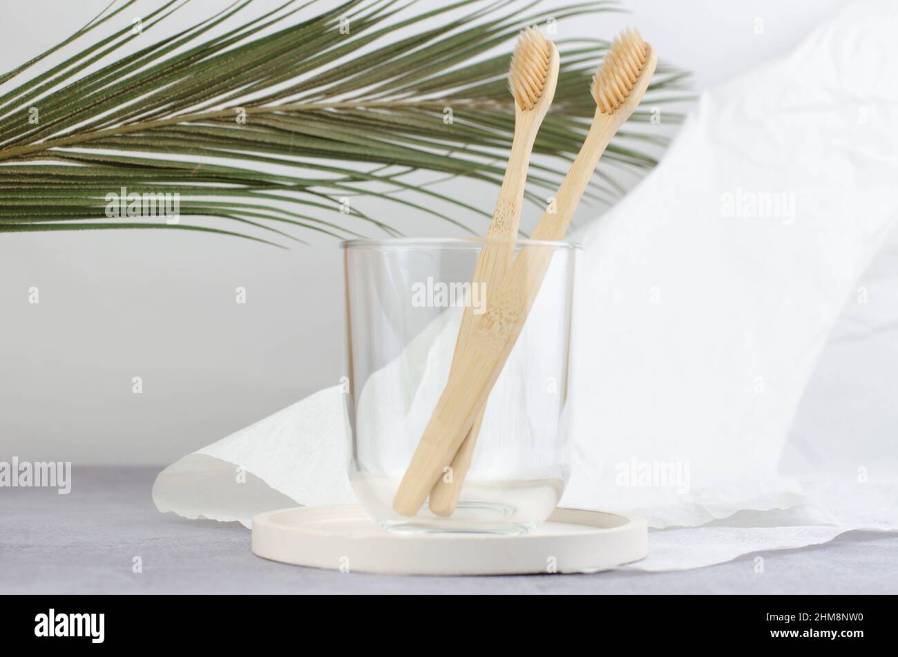 Due spazzolini in legno in un vaso di vetro trasparente. Cura orale. Foto Stock