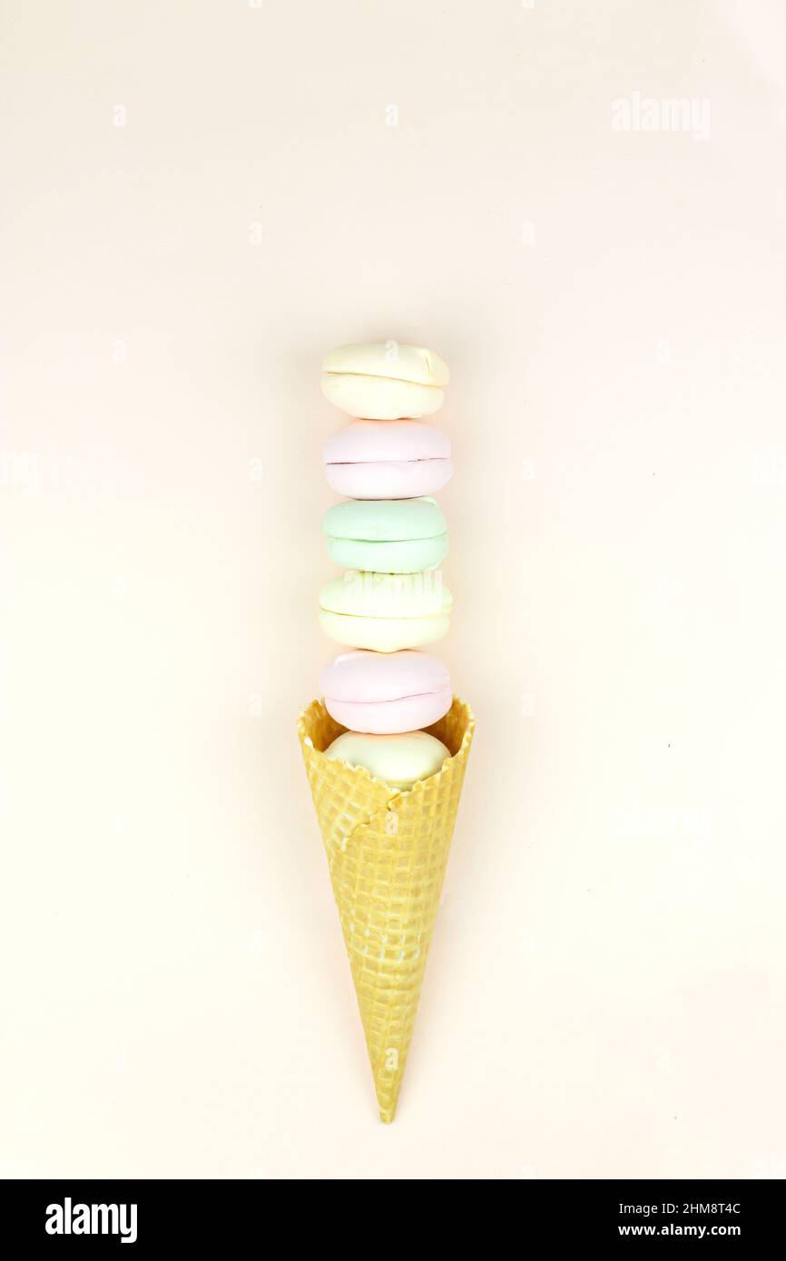Delizioso sotto forma di un cono waffle farciti marshmallow assomiglia a macaroon su sfondo rosa, concetto di dolce dessert. Foto Stock