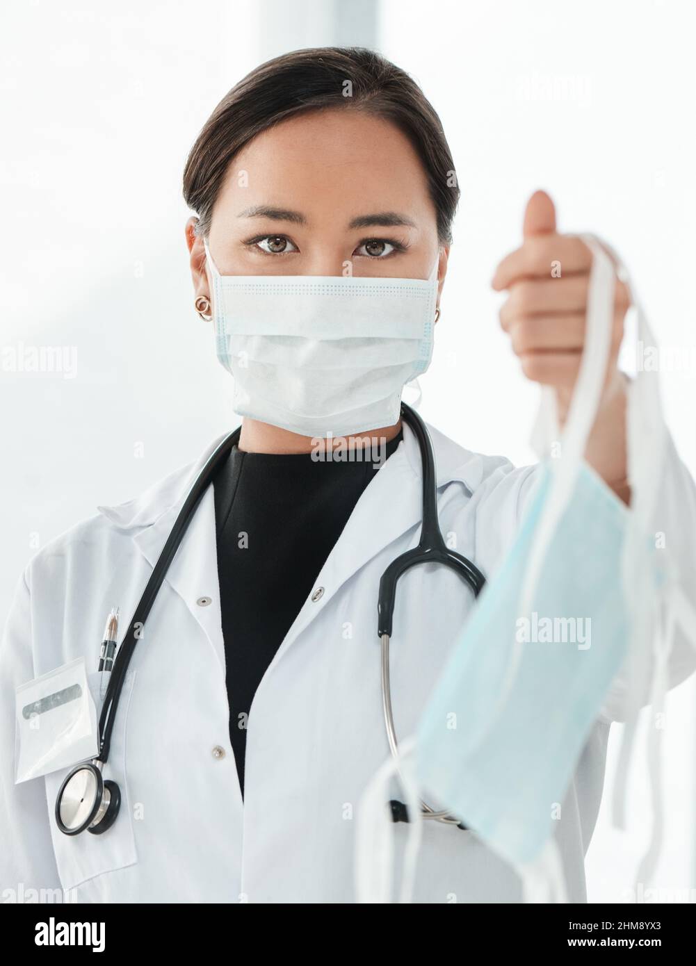 Questo è il nostro consiglio di limitare la diffusione del coronavirus. Scatto ritagliato di un medico che tiene in mano una maschera facciale. Foto Stock