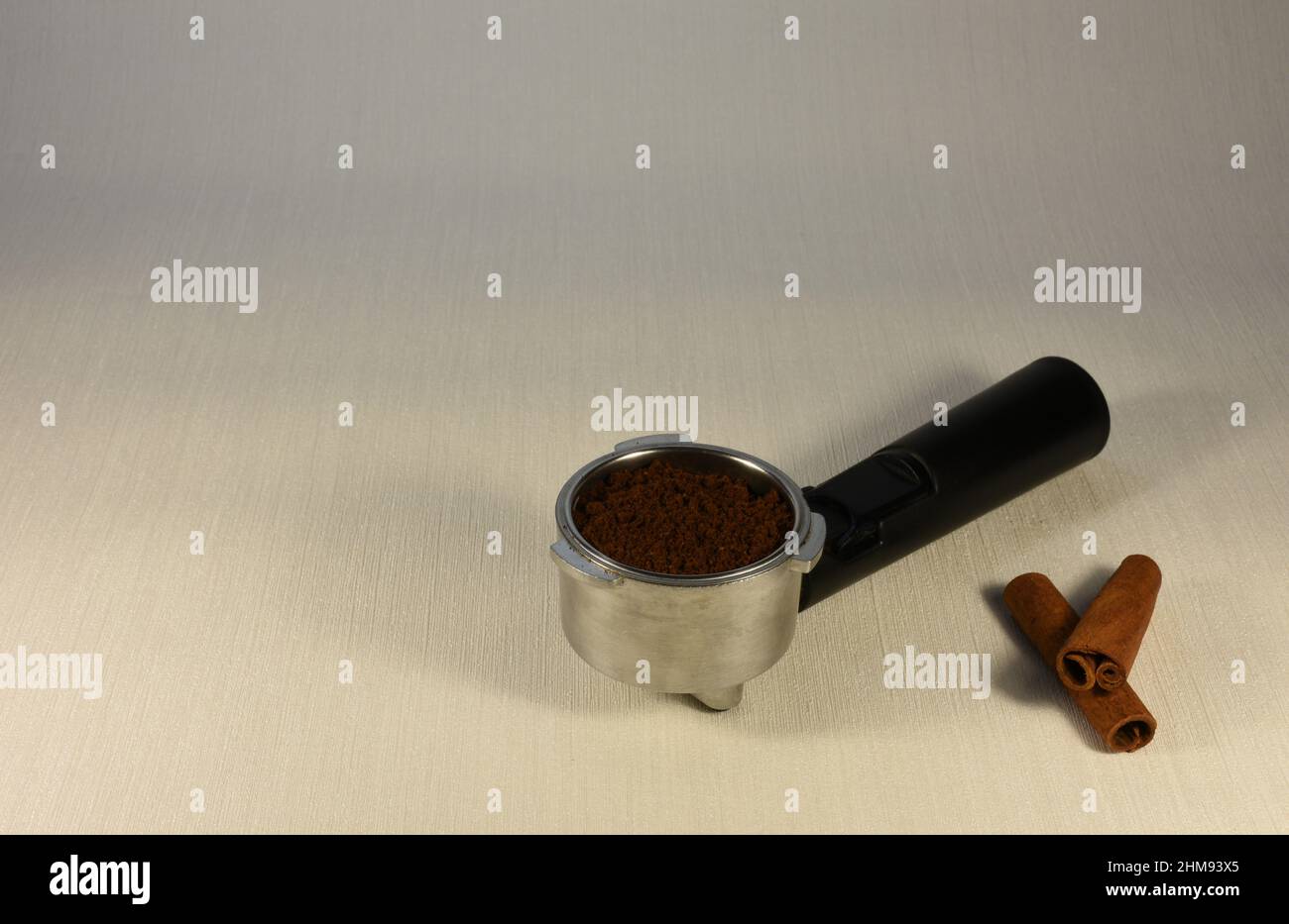 Filtro del caffè e bastoncini di cannella su sfondo chiaro. Foto Stock