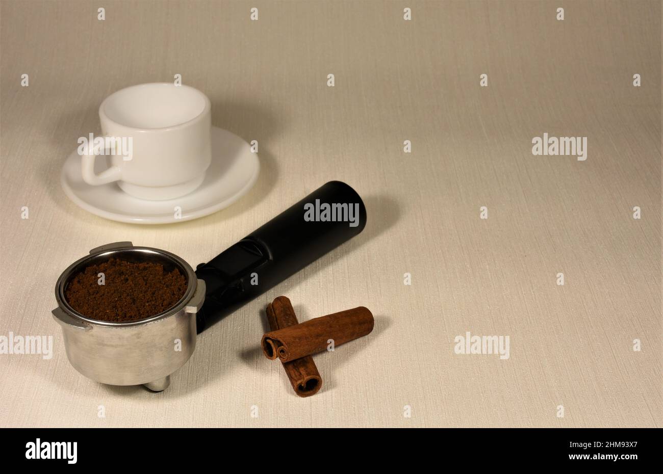 Tazza di caffè in porcellana bianca vuota, filtro per caffè e bastoncini di cannella su sfondo chiaro. Foto Stock