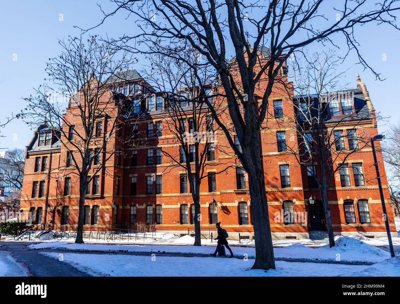 Cambridge, Massachusetts, Stati Uniti d'America - 6 febbraio 2022: Gli studenti passano accanto a Weld Hall nell'Harvard Yard dell'Università di Harvard in una giornata invernale. Costruito nel 1 Foto Stock