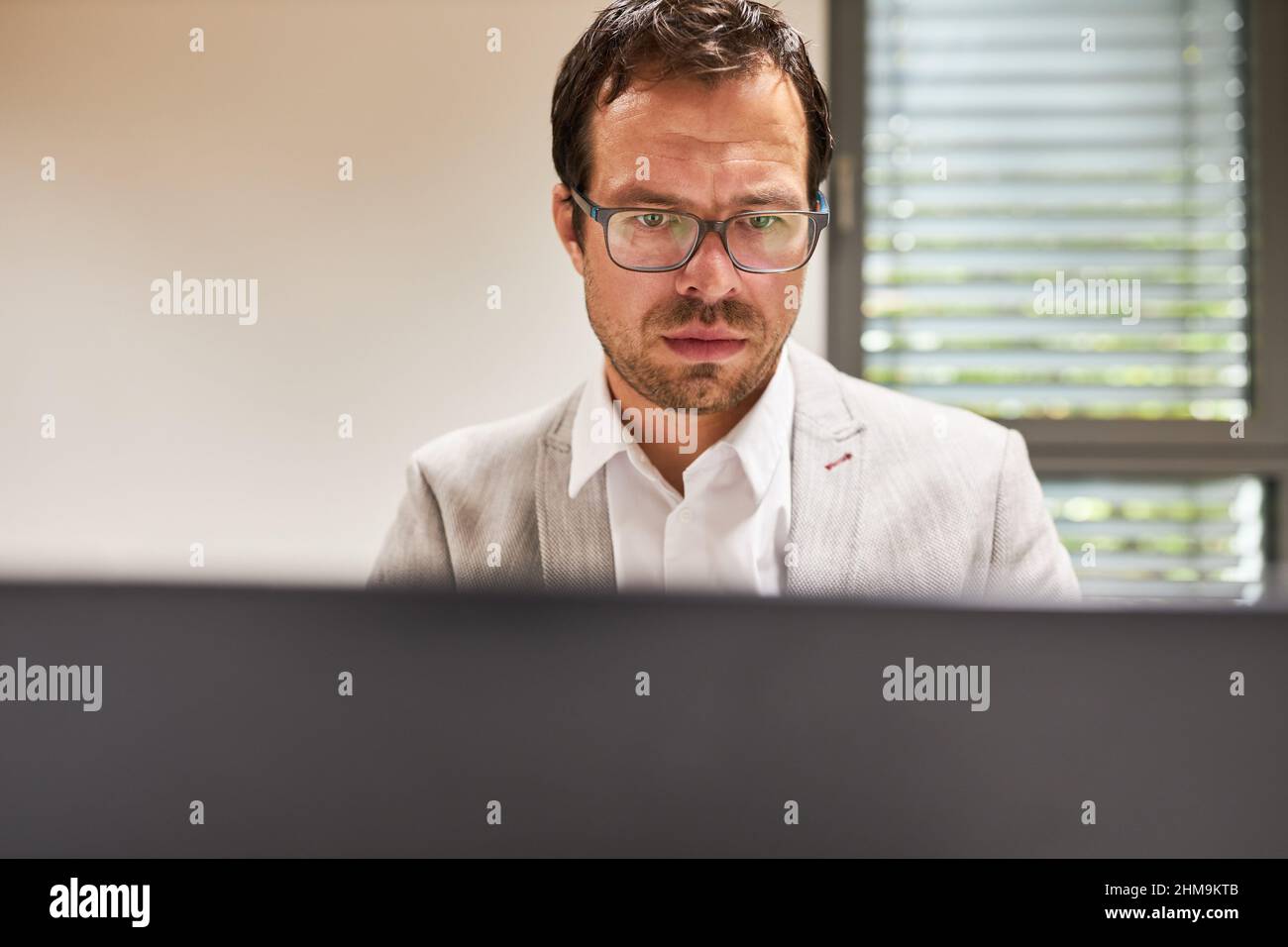 L'uomo d'affari che lavora concentrato sul calcolatore in linea o come programmatore in ufficio Foto Stock
