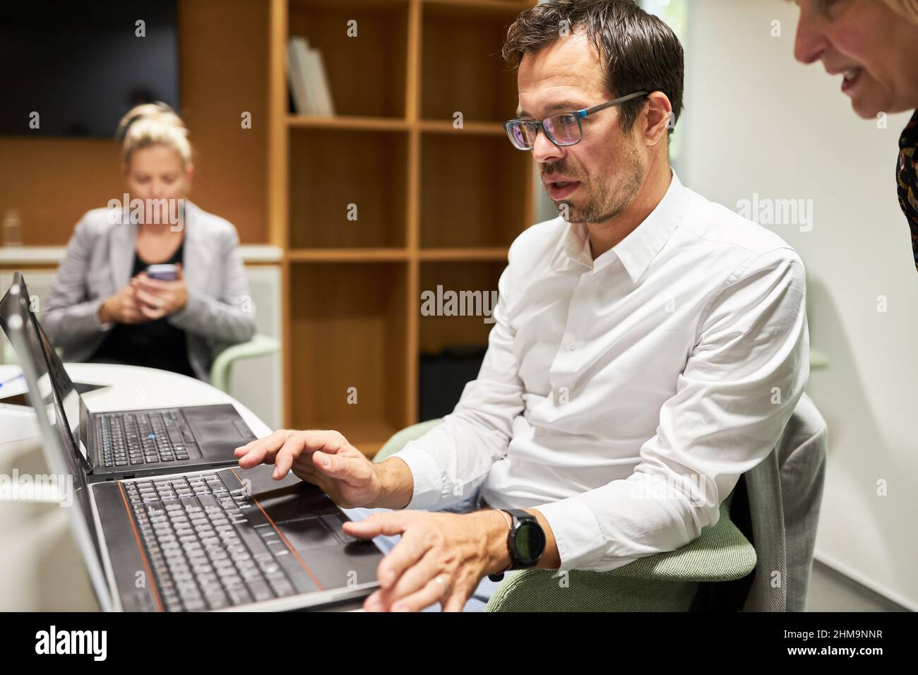 Il personale aziendale lavora insieme su un PC portatile in classe informatica o nello sviluppo di software Foto Stock