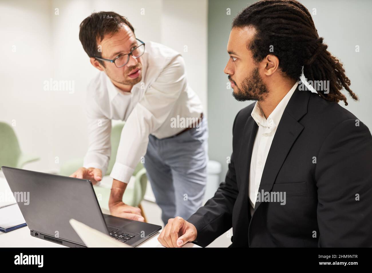 Due persone aziendali, in qualità di programmatori, discutono dello sviluppo di software sul PC portatile in ufficio Foto Stock