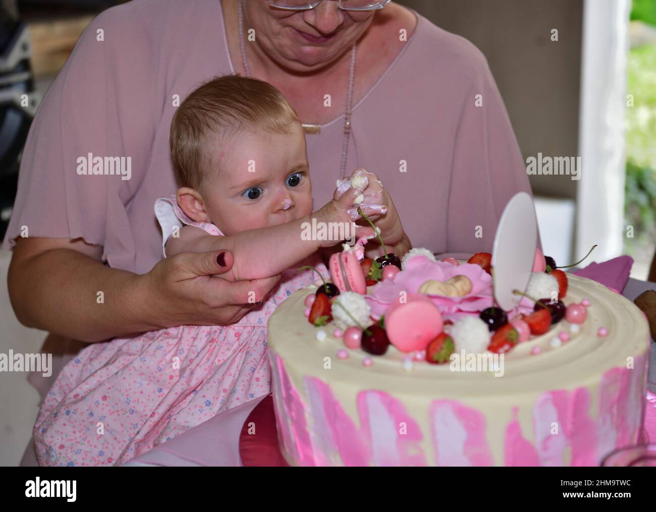 Bambina neonato di 1 anni con le mani che toccano la torta durante la festa di compleanno Foto Stock