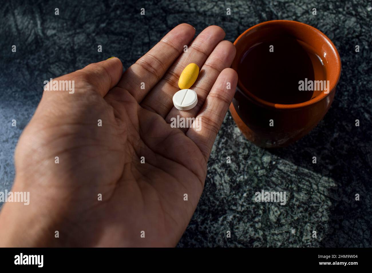 Persona paziente che consuma farmaci prescritti compresse in mano. Bicchiere d'acqua Foto Stock