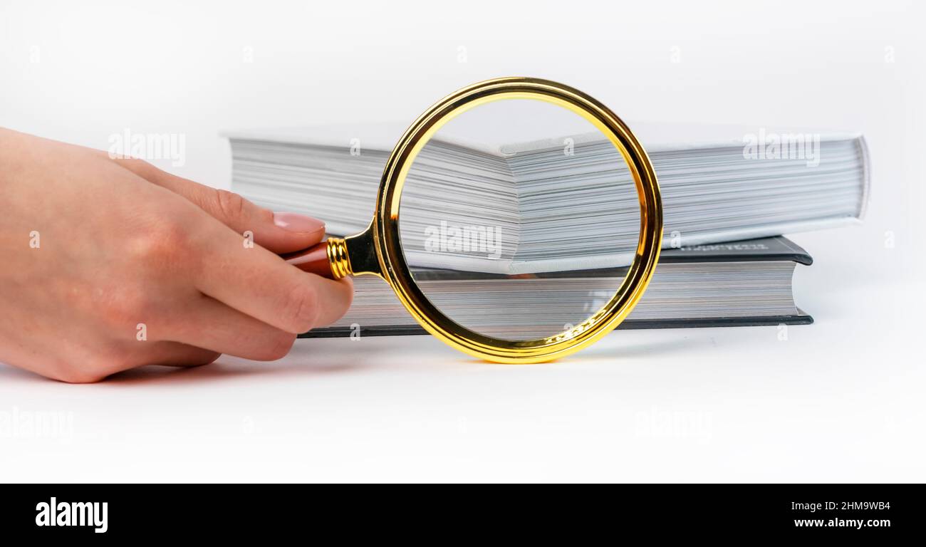 Libri e lente d'ingrandimento in mano. Concetto di ricerca e analisi delle informazioni. Foto di alta qualità Foto Stock