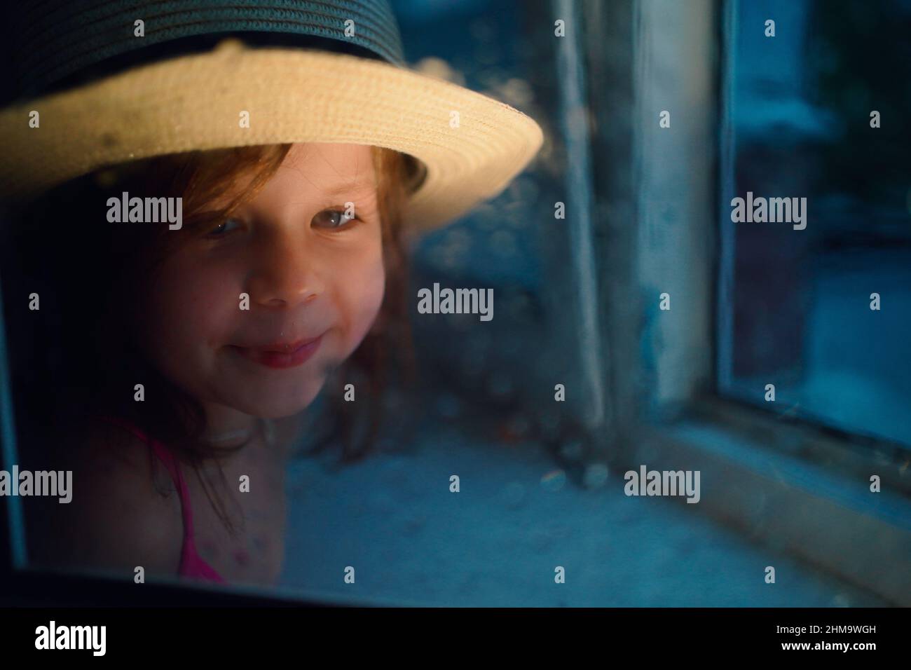 una ragazza in un cappello di paglia, pioggia fuori dalla finestra Foto Stock
