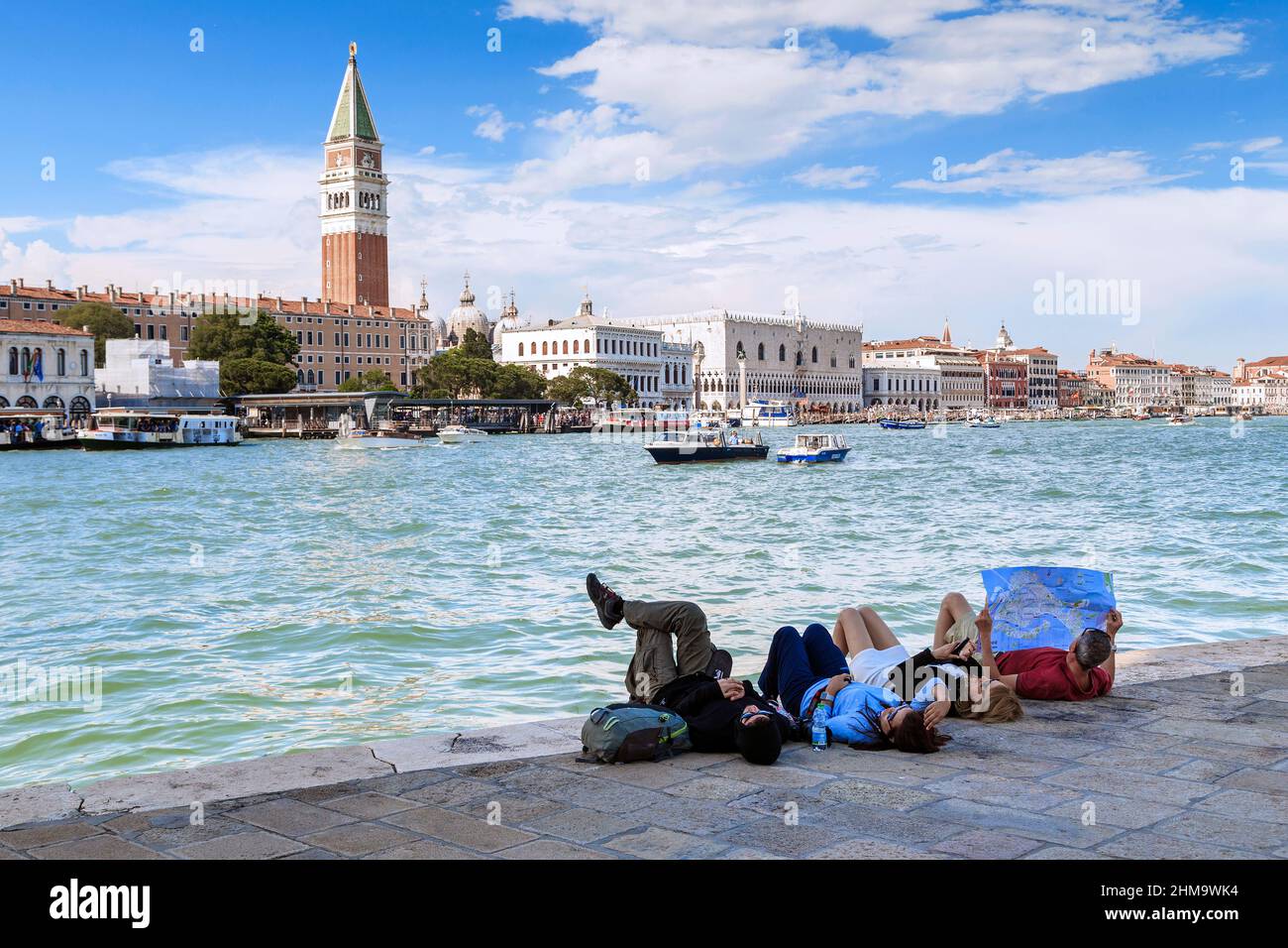 VENEZIA, ITALIA - 18 MAGGIO 2018: Un gruppo di turisti non identificati poggia sulle rive del Canal Grande con una mappa della città. Foto Stock