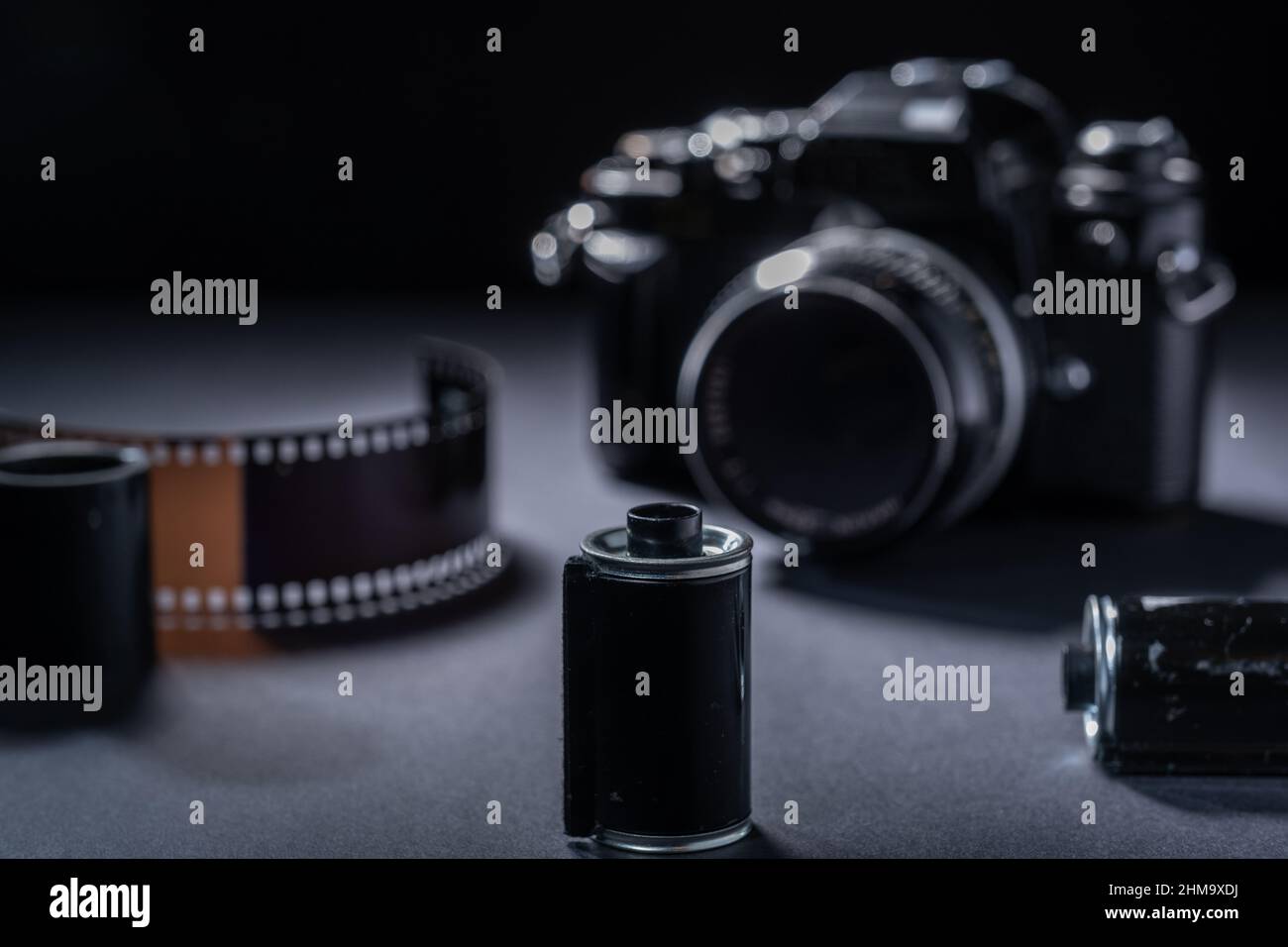 Fotografia di film - una cartuccia di film metallico vintage e una fotocamera reflex 35mm su sfondo scuro. Foto Stock