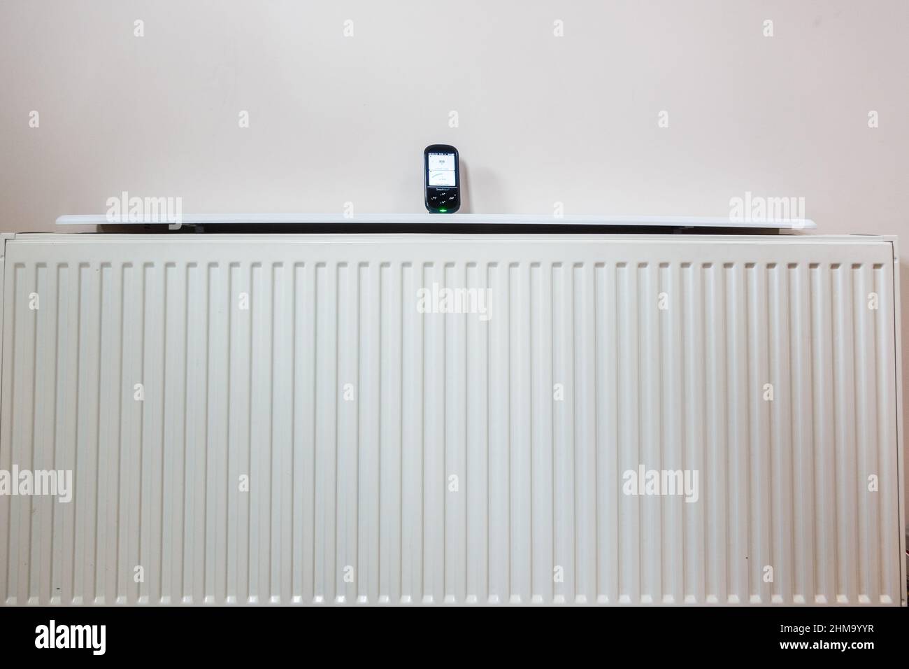 Il contatore intelligente dell'energia elettrica e del gas utilizzato nel Regno Unito viene visualizzato su un radiatore per stanza, indicando il costo dell'aumento del prezzo del gas Foto Stock