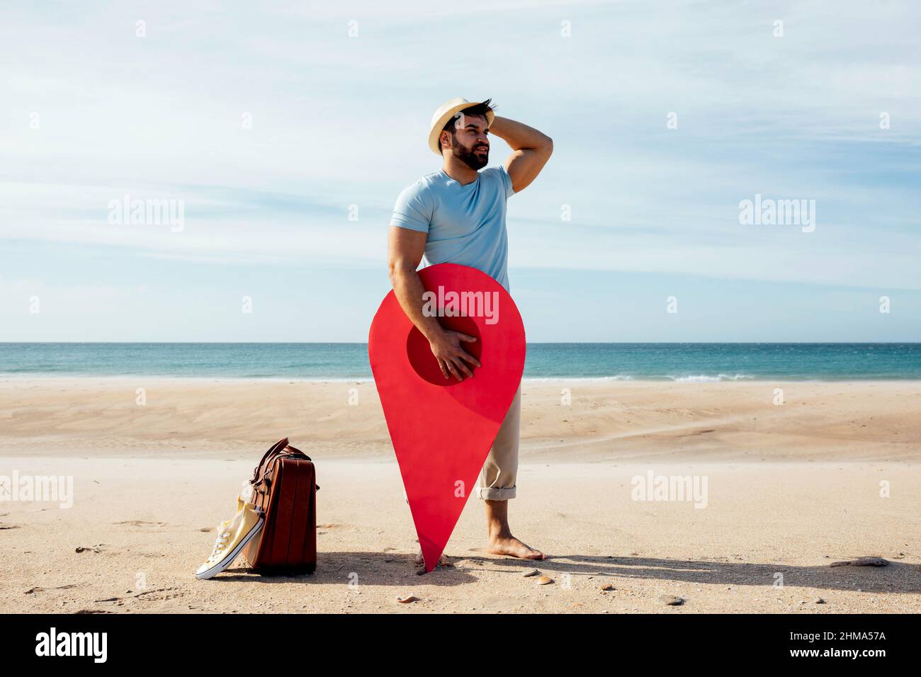 Perso maschio turista in piedi con pin posizione rossa sulla spiaggia di sabbia contro il mare e alla ricerca di direzione Foto Stock