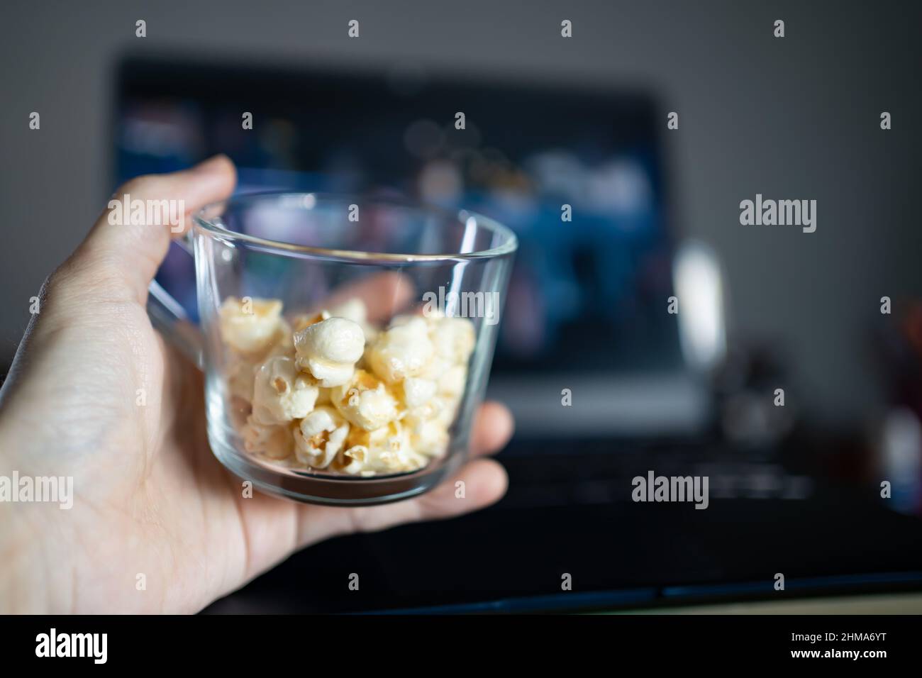 Mangiare popcorn mentre si guarda un film su un computer portatile Foto Stock