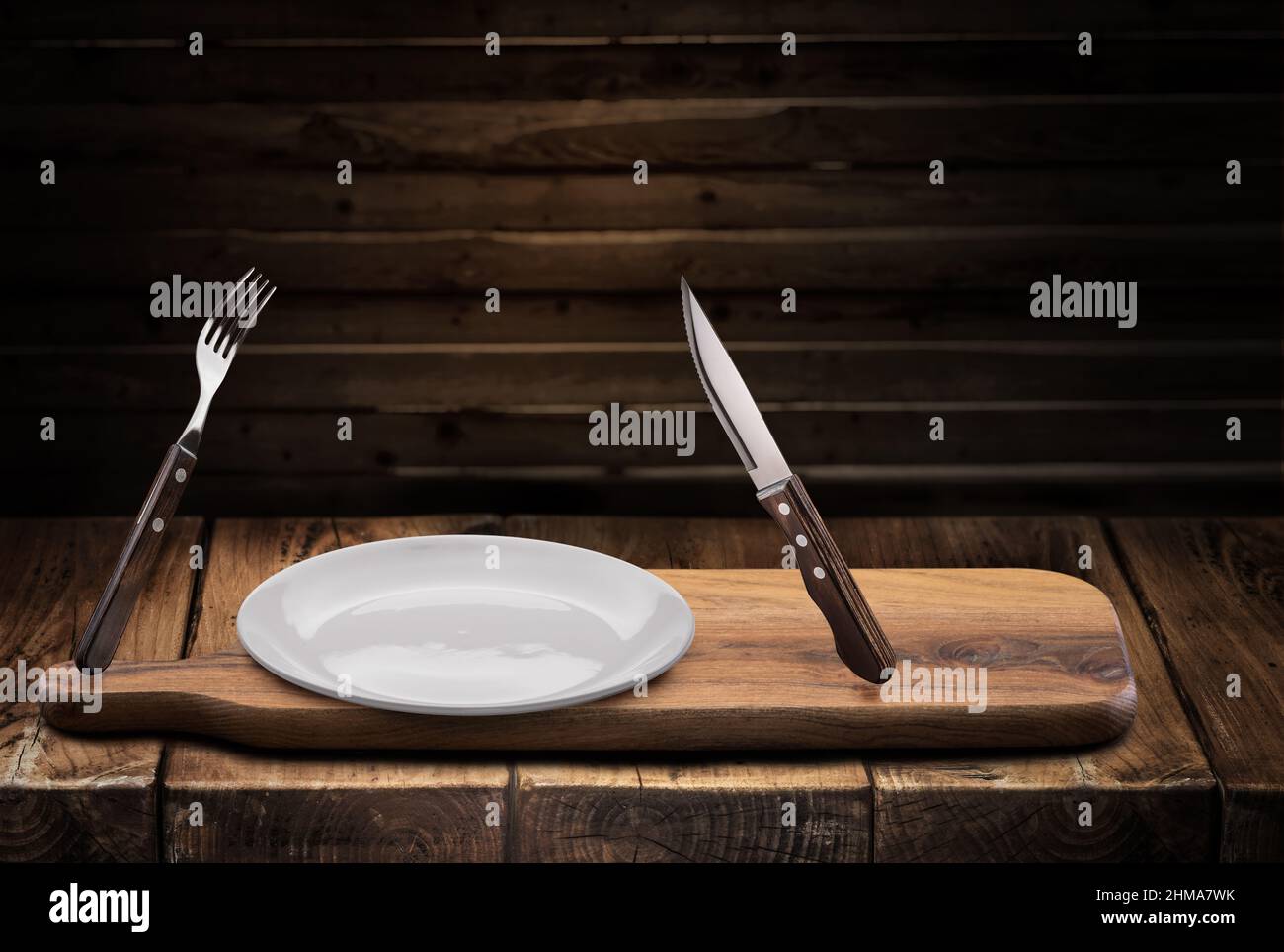 Immagine concettuale del pasto preso. Svuotare la piastra bianca, la forcella e il coltello vicino ad essa nell'aria. Foto Stock