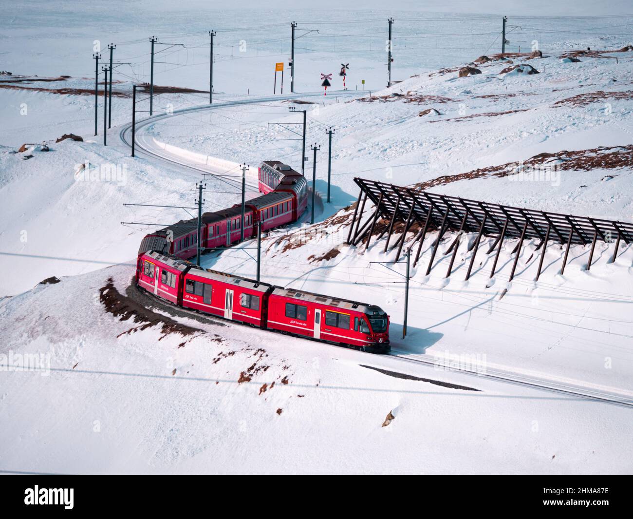 Berninapass, Svizzera - 19 gennaio 2022: Treno panoramico turistico rosso Bernina Express che corre tra Chur e Tirano in Italia e attraversa la neve cov Foto Stock