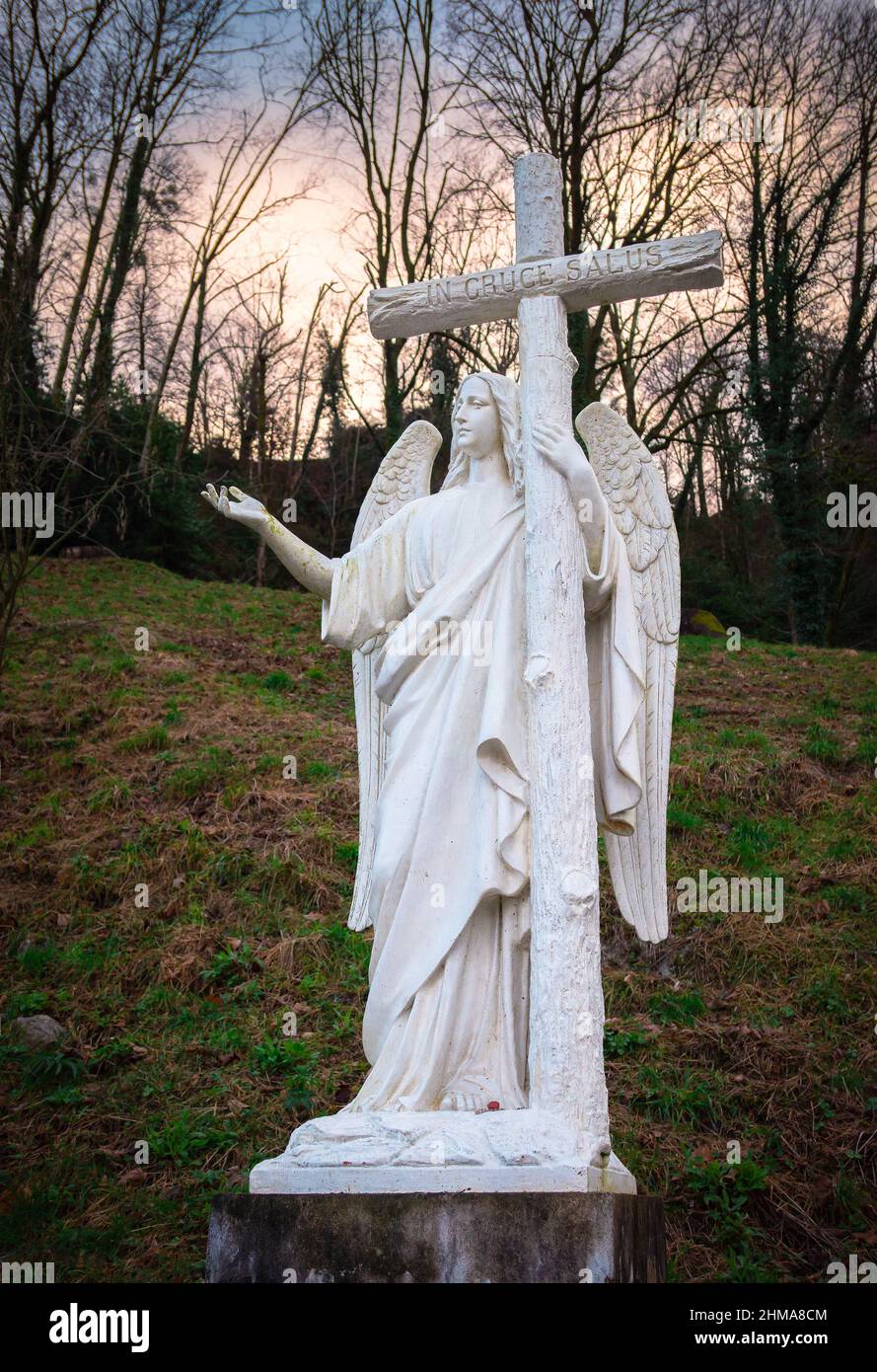 Lourdes, Francia - 5 gennaio 2022: Scultura bianca dell'angelo con la croce con l'iscrizione latina in cruce salus - tradotto in inglese: Nella c Foto Stock