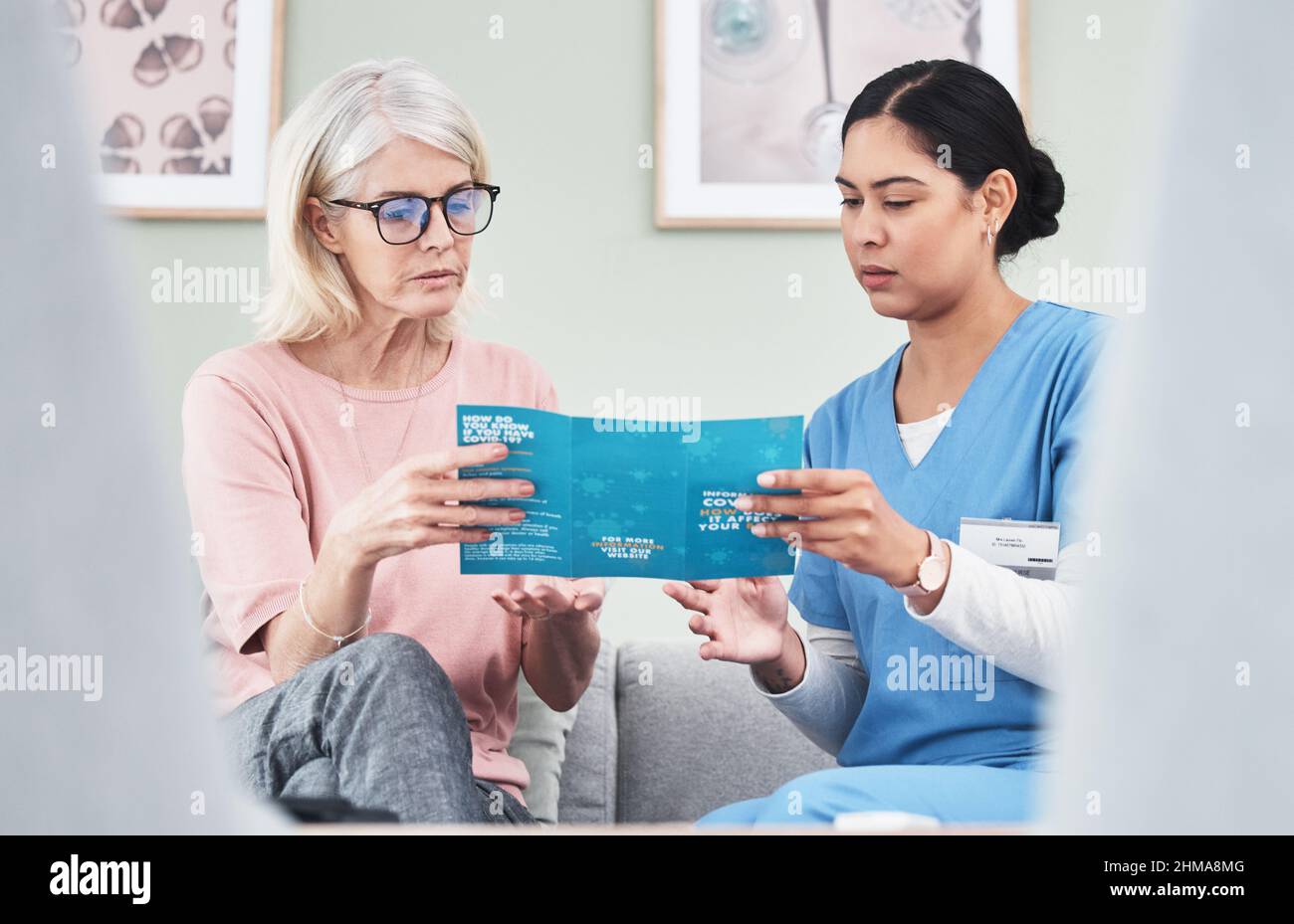 La conoscenza è la migliore difesa. Shot di una nutrice femminile che legge attraverso un opuscolo Covid-19. Foto Stock