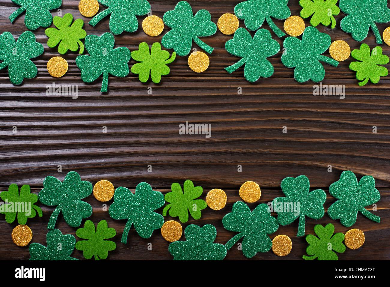 Foglie e monete di Clover fatte a mano su sfondo di legno piatto vista Foto Stock