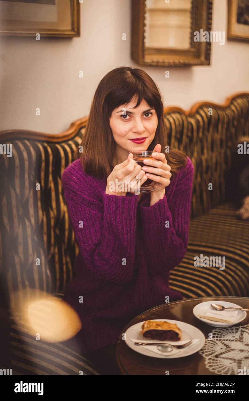 Accogliente stile di vita di splendide donne europee che indossano un pullover alla moda, gustando aroma e sapore di caffè mentre si rilassano nel vecchio e accogliente caffè di Budapest, Foto Stock