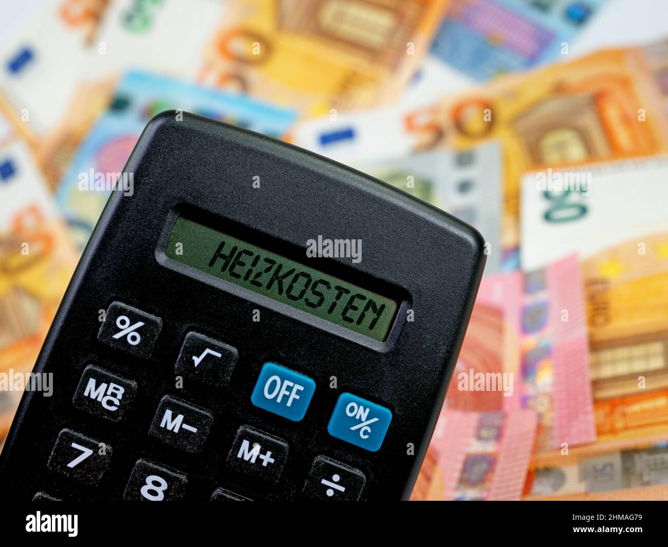 Calcolatrice con la parola 'Heizkosten', traduzione 'costi di riscaldamento'  sul display di fronte alle banconote Foto stock - Alamy