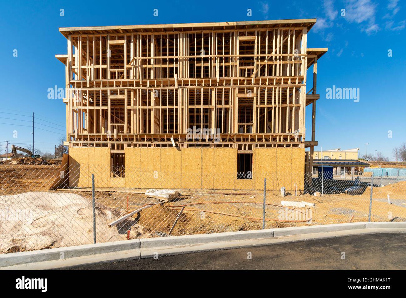 Scatto orizzontale di un nuovo complesso di appartamenti in costruzione dietro una recinzione di filo. Foto Stock